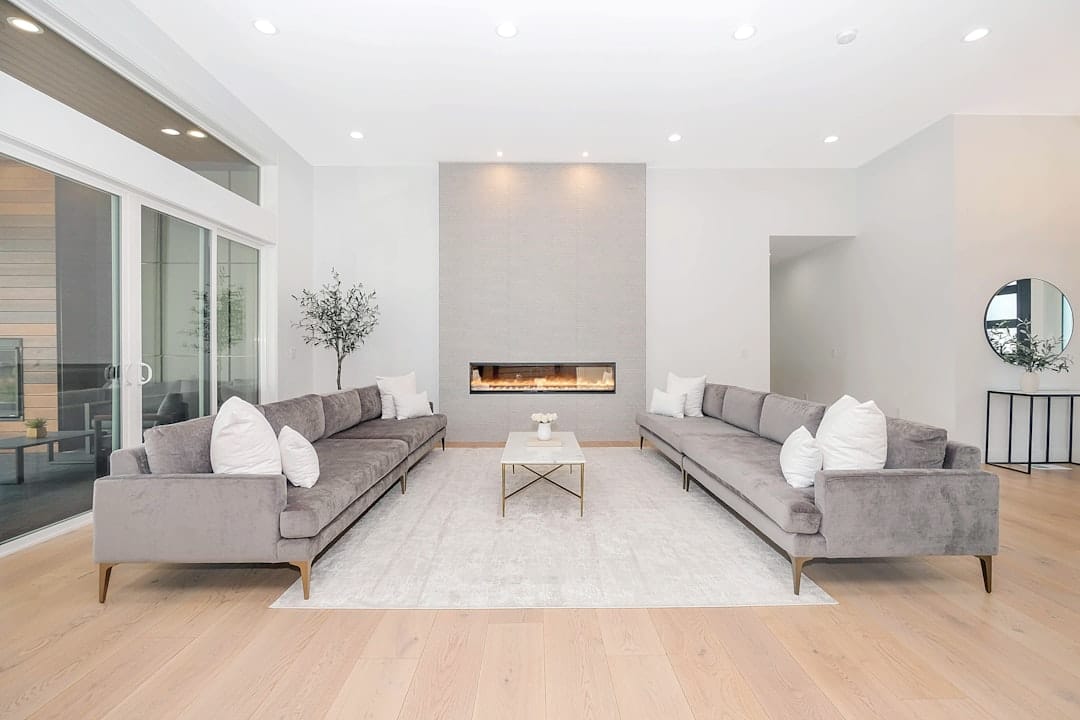 A professional and friendly real estate agent uses a tablet inside a bright, modern living room, showcasing the tech-enabled, full-service nature of a lean business model.