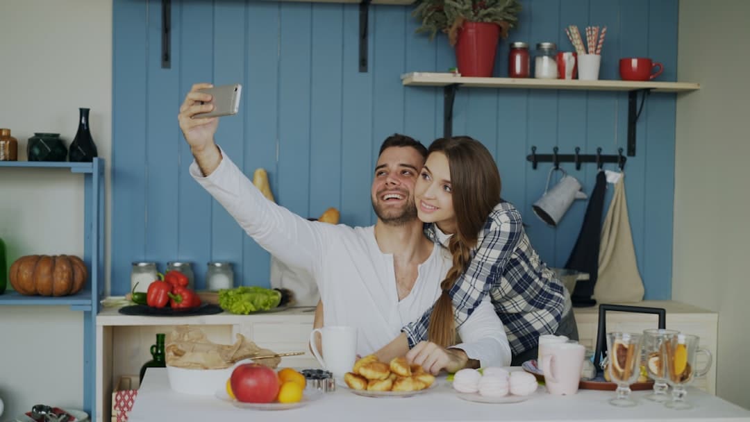 A smiling couple stands in their professionally designed, light-filled kitchen, symbolizing homeowner satisfaction and financial well-being.