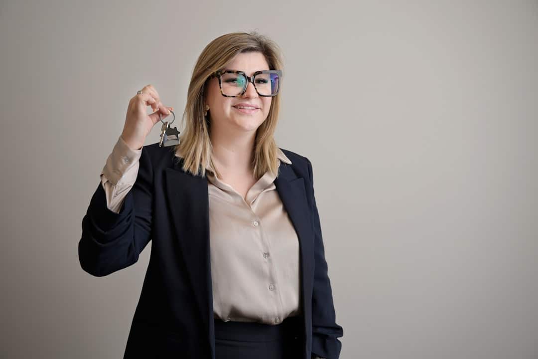A close-up, professional shot of a person's hand giving modern house keys to another person, signifying a successful and finalized home sale.