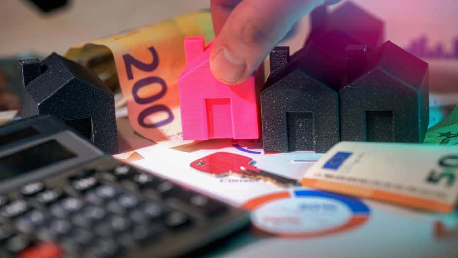 Bright, professional photo of house keys and a calculator resting on a modern wooden desk, symbolizing the financial analy...