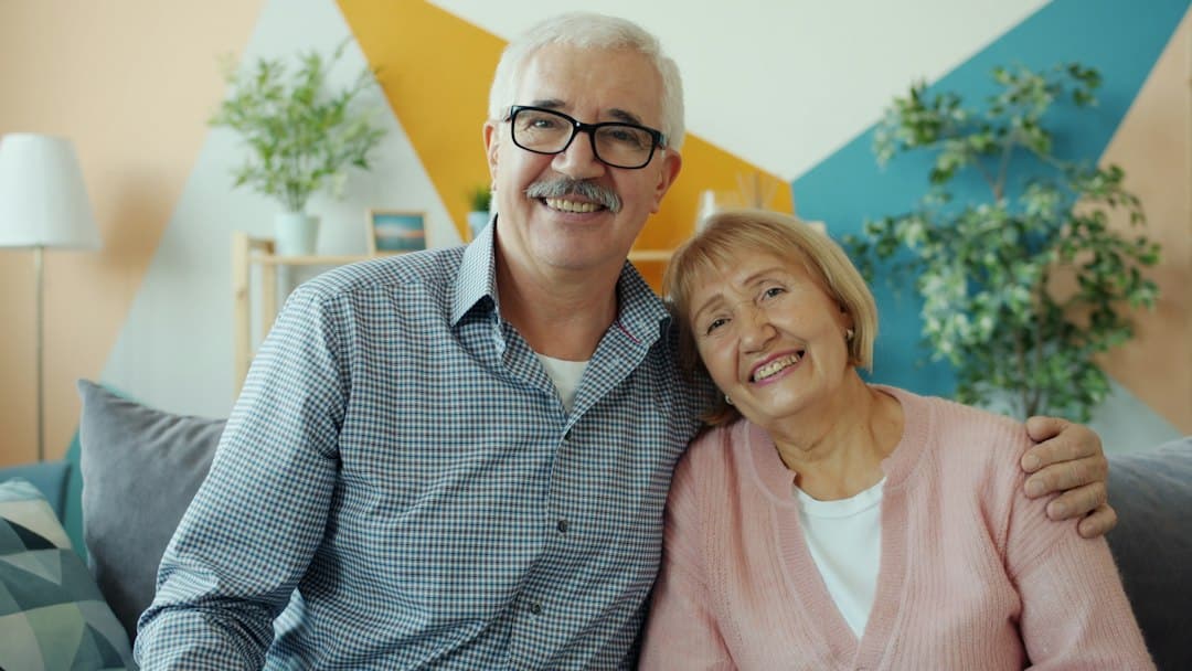 A happy couple relaxes in their beautifully decorated, light-filled modern living room, representing the financial peace of mind from saving on commission fees.