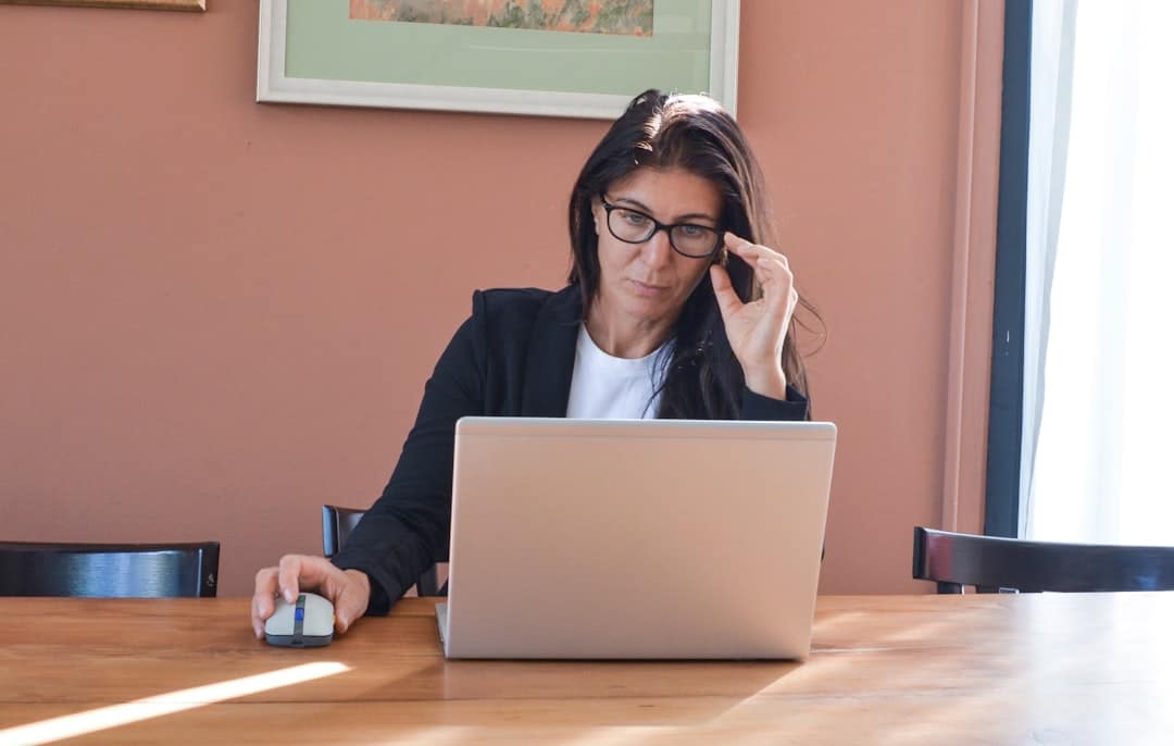 Homeowner sits at their dining room table looking overwhelmed by a pile of official documents and a laptop, illustrating t...