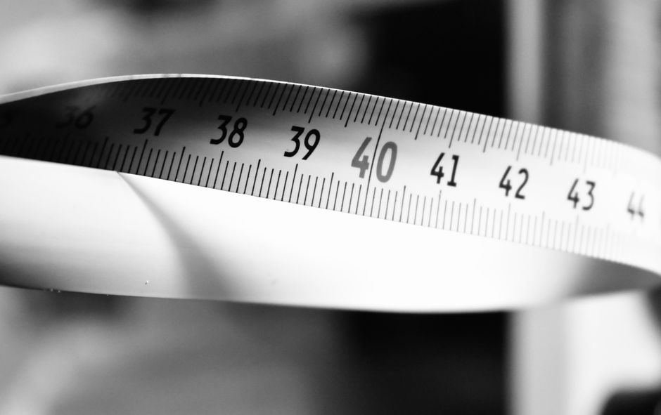 A tangled metal measuring tape lies on a clean, minimalist surface, symbolizing the hidden complexities and financial pitfalls of selling a home without a professional realtor.
