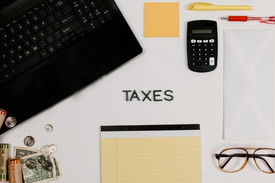 A clean, minimal flat lay of house keys, a calculator, a pen, and paperwork on a desk, illustrating the financial components of a real estate transaction.
